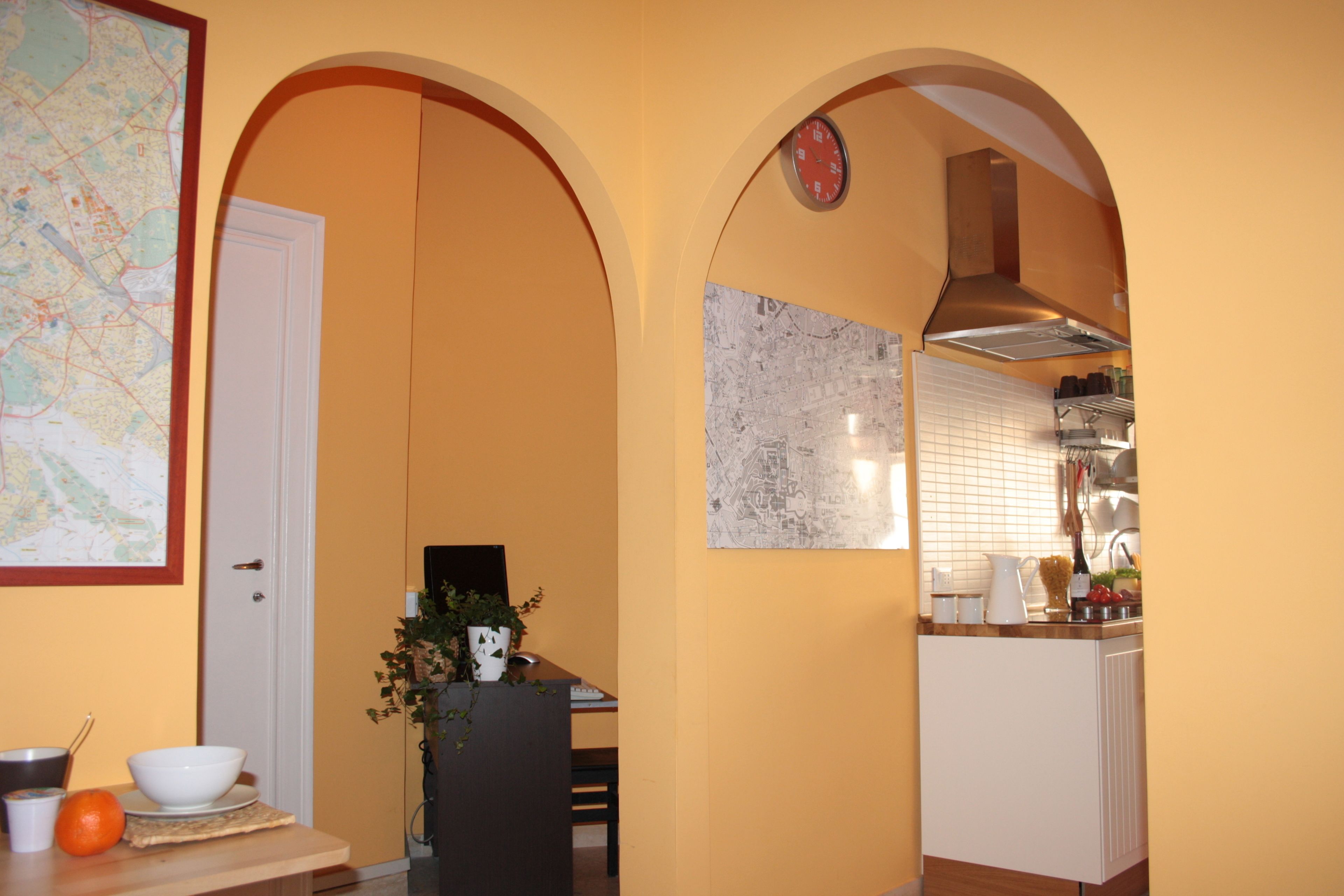 A kitchen with white cabinets, a map on the wall, and a clock.
