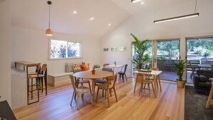 A spacious living area with a wooden dining table, chairs, and a large window offering a view of the outdoors. - Sunny Side Up B&B (Rye)