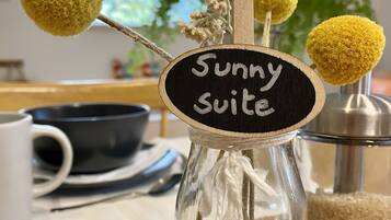 Eine klare Glasflasche mit dem Aufkleber "Sunny Suite" und dekorativen gelben Pompons.