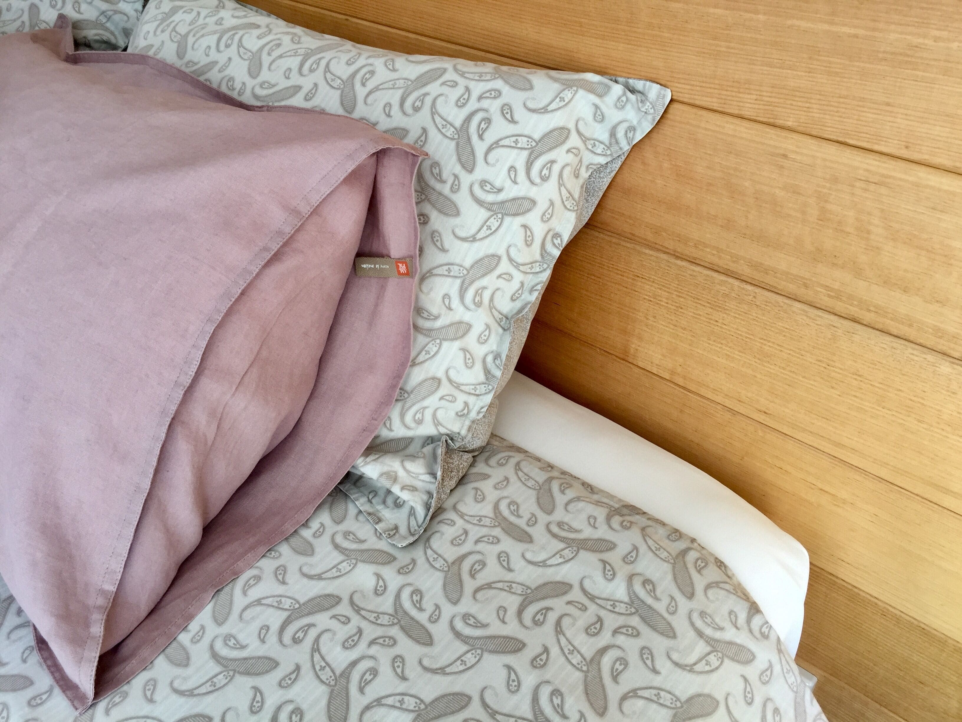 A bed with a pink pillow and patterned bedding.