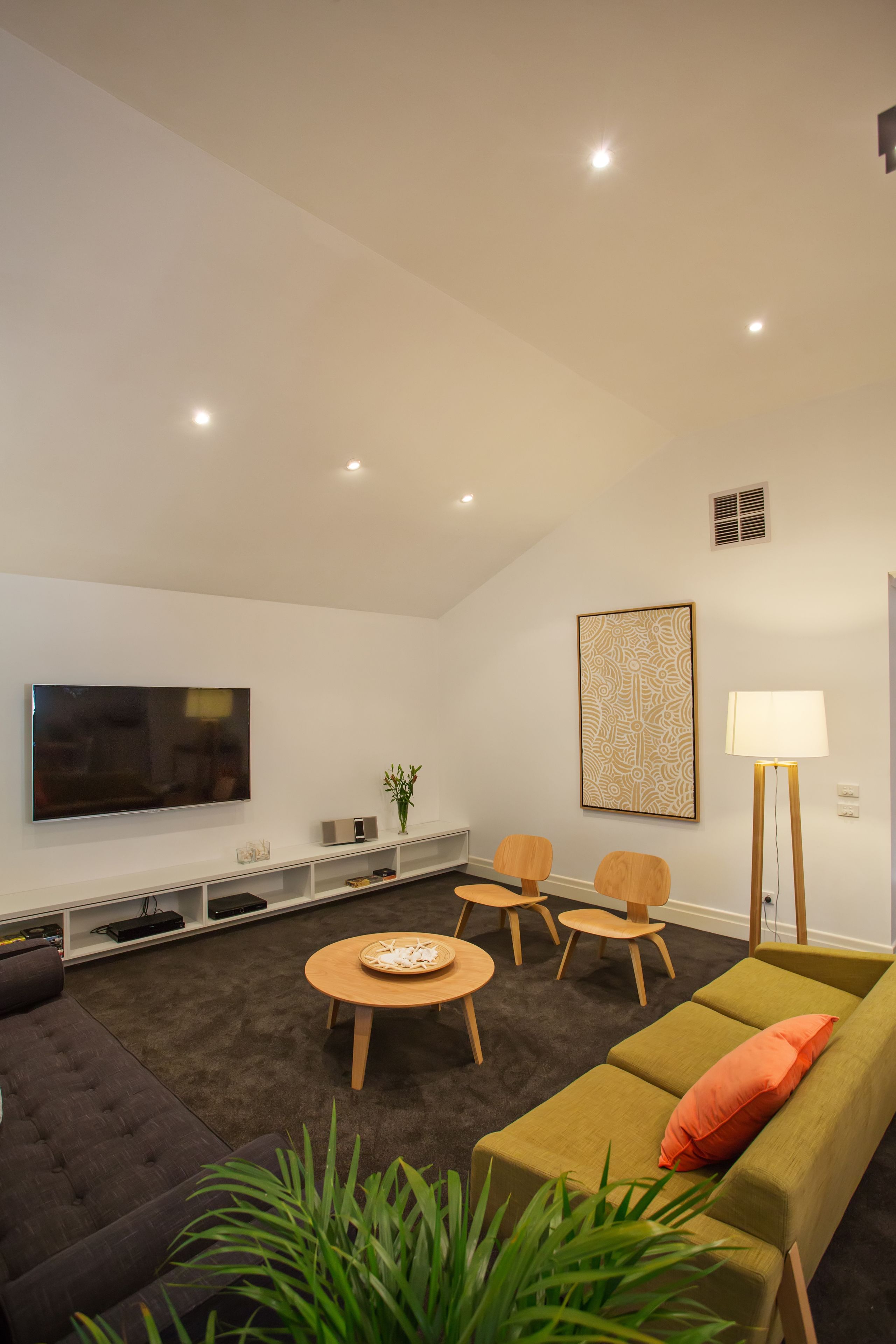 A modern living room with a flat-screen TV, a sofa, a coffee table, and a lamp.