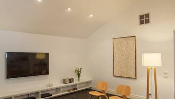 A modern living room with a flat-screen TV, a sofa, a coffee table, and a lamp.