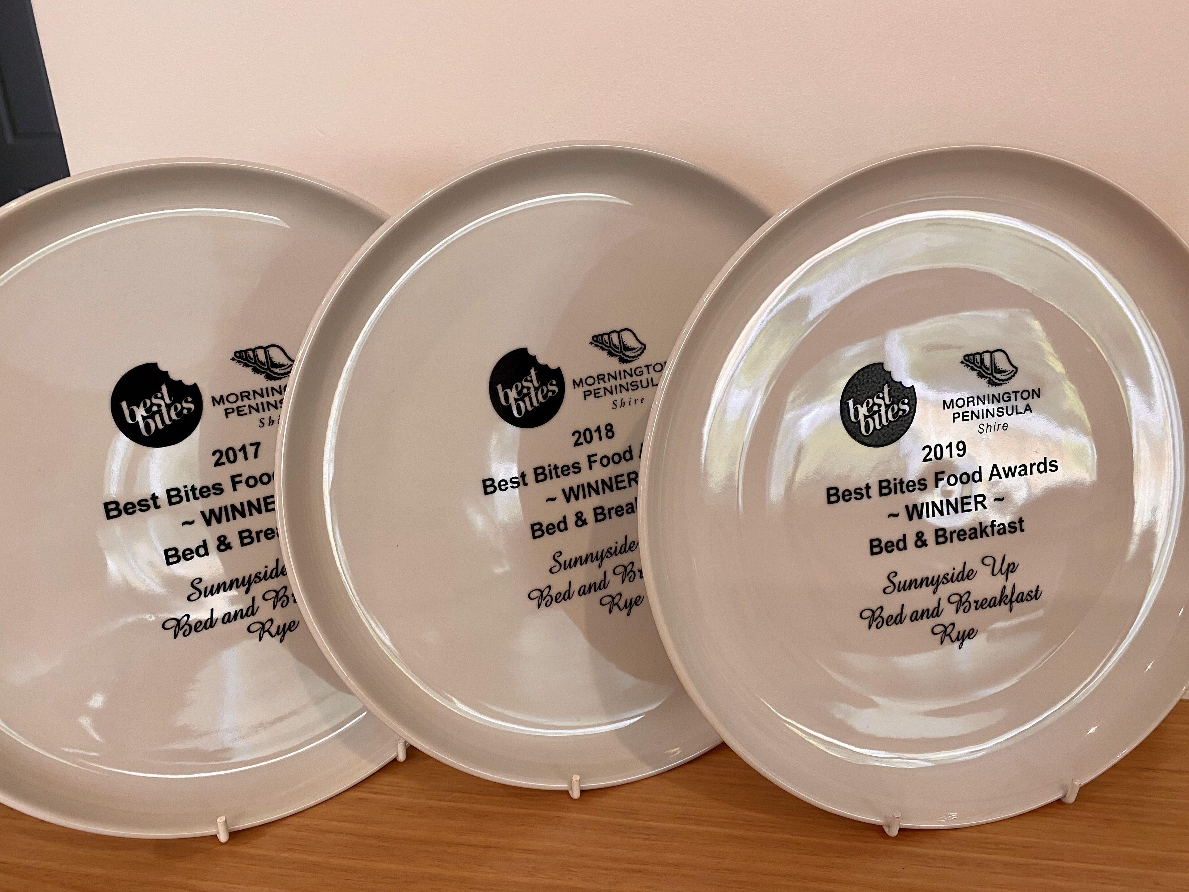 Tres platos con premios de los Best Bites Food Awards, reconociendo los servicios del Bed & Breakfast.