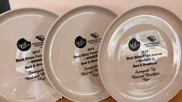 Tres platos con premios de los Best Bites Food Awards, reconociendo los servicios del Bed & Breakfast.