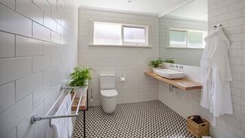A bathroom with white tiled walls, a toilet, a sink, and a window.