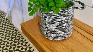A bathroom with a patterned floor, a wooden shelf, and a potted plant with a black and white zigzag pattern.