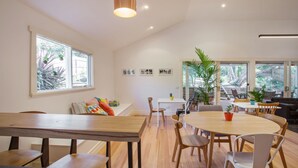 A spacious room with a large wooden dining table, multiple chairs, and a ceiling light fixture. - Sunny Side Up B&B (Rye)