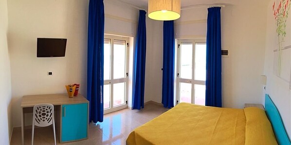 A room with a bed, a desk with a chair, a small cabinet, and a television on the wall. - Hotel Albatros (Morciano di Leuca)