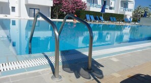 Una piscina al aire libre de temporada, sombrillas