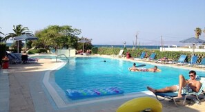 Una piscina al aire libre de temporada, sombrillas