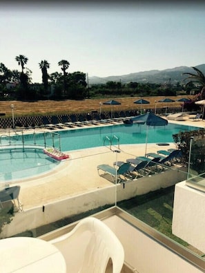 Una piscina al aire libre de temporada, sombrillas