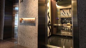 An elevator with a metallic finish, a control panel, and a glass door with a geometric pattern. - WESTGATE Hotel (Taipei)