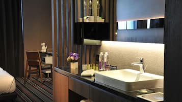 Un baño moderno con un espejo grande, un lavamanos y una silla.