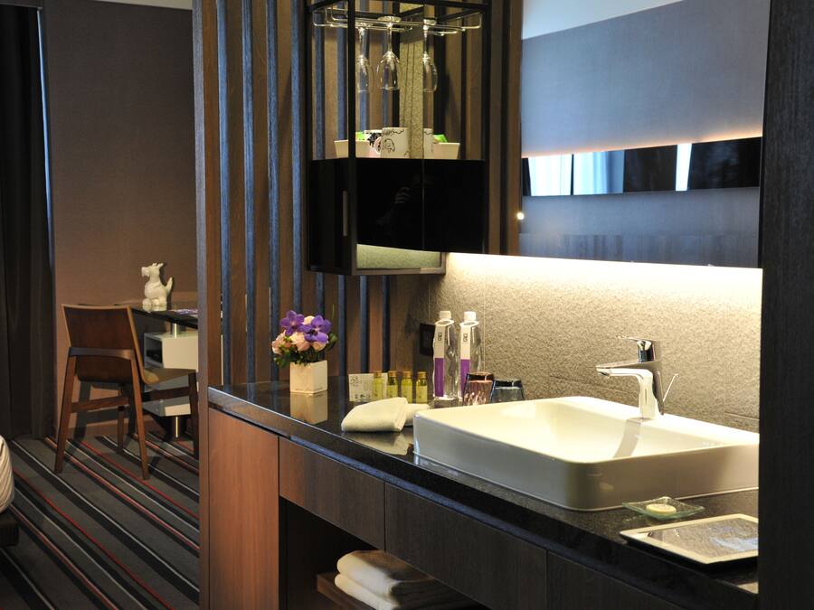 Un baño moderno con un espejo grande, un lavamanos y una silla.