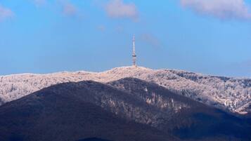 Ein Turm auf einem mit Schnee bedeckten Hügel vor blauem Himmel.