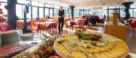 A buffet with various food items and a waiter in the background.