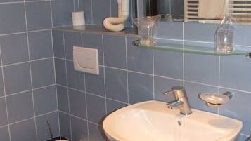A bathroom with a toilet, bidet, sink, and a mirror with a towel rack.