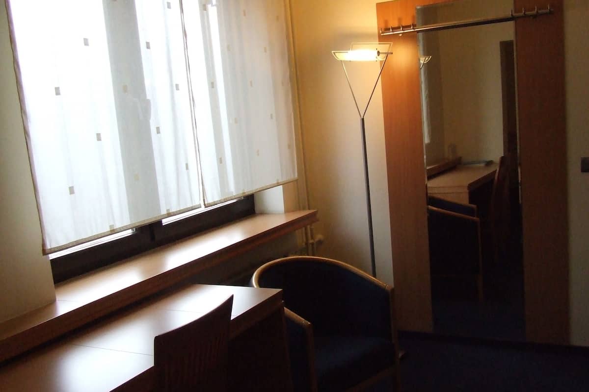 A hotel room with a desk, chair, and a large mirror.