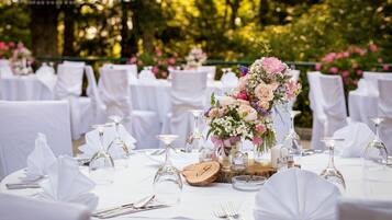 A table set for a formal event with white tablecloths, glassware, and floral centerpieces.