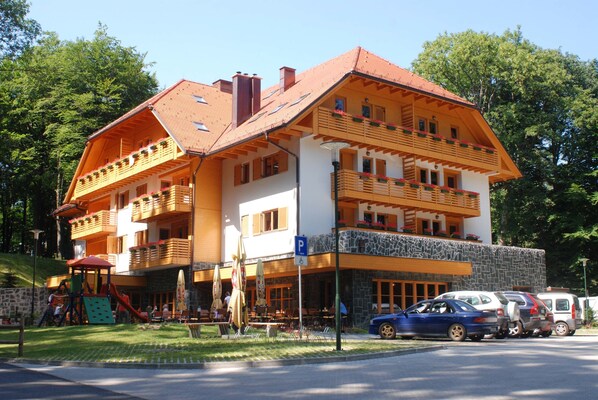 A multi-story building with a sloped roof, balconies, and a ground-level restaurant area. - Aparthotel Snjezna Kraljica (Stubicke Toplice)