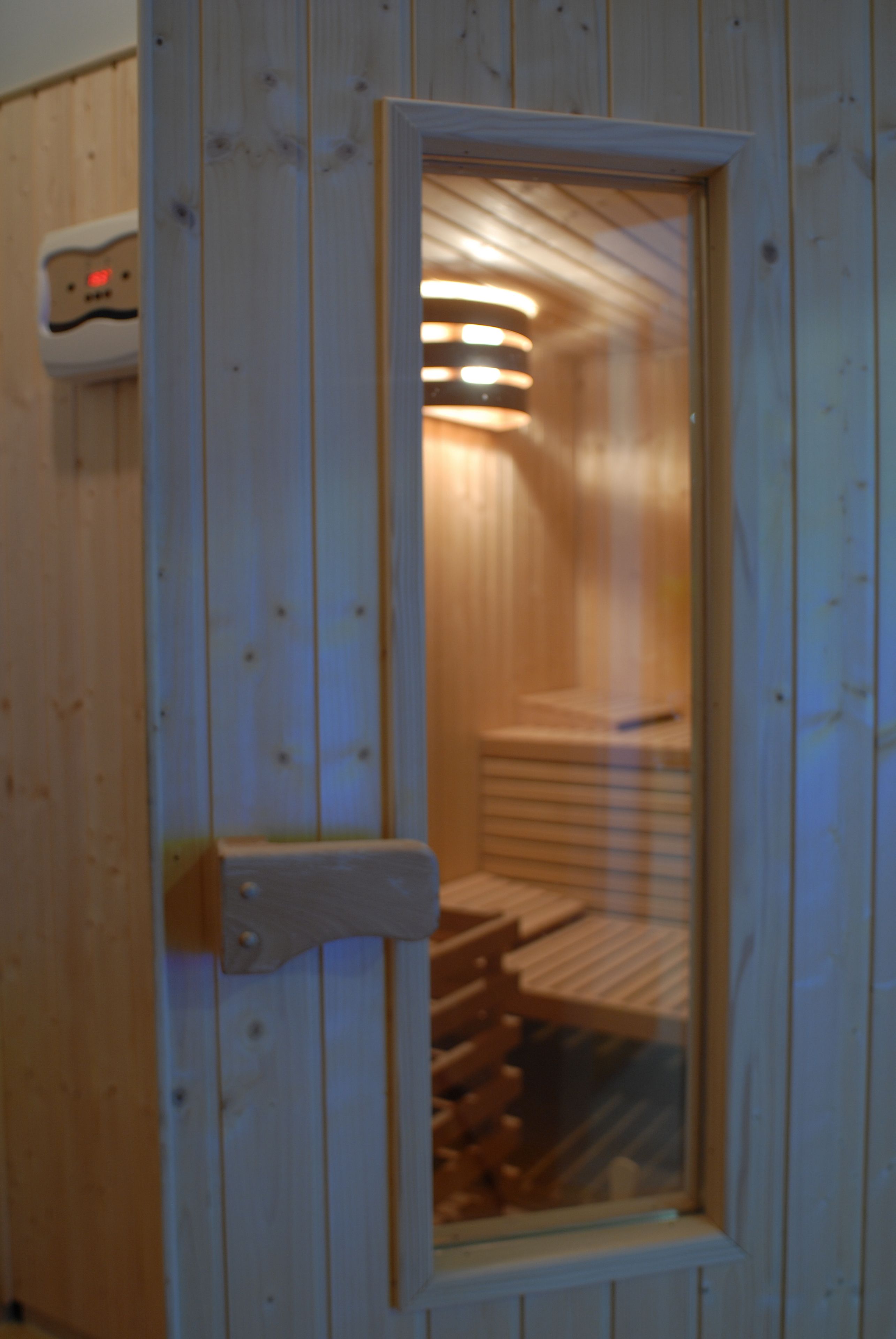 Eine Sauna mit Holzwänden und einer Glastür.