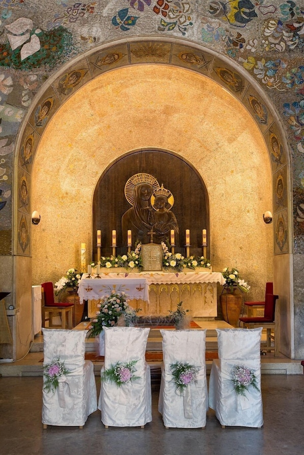 An altar with a religious icon, candles, and floral arrangements in a church setting.
