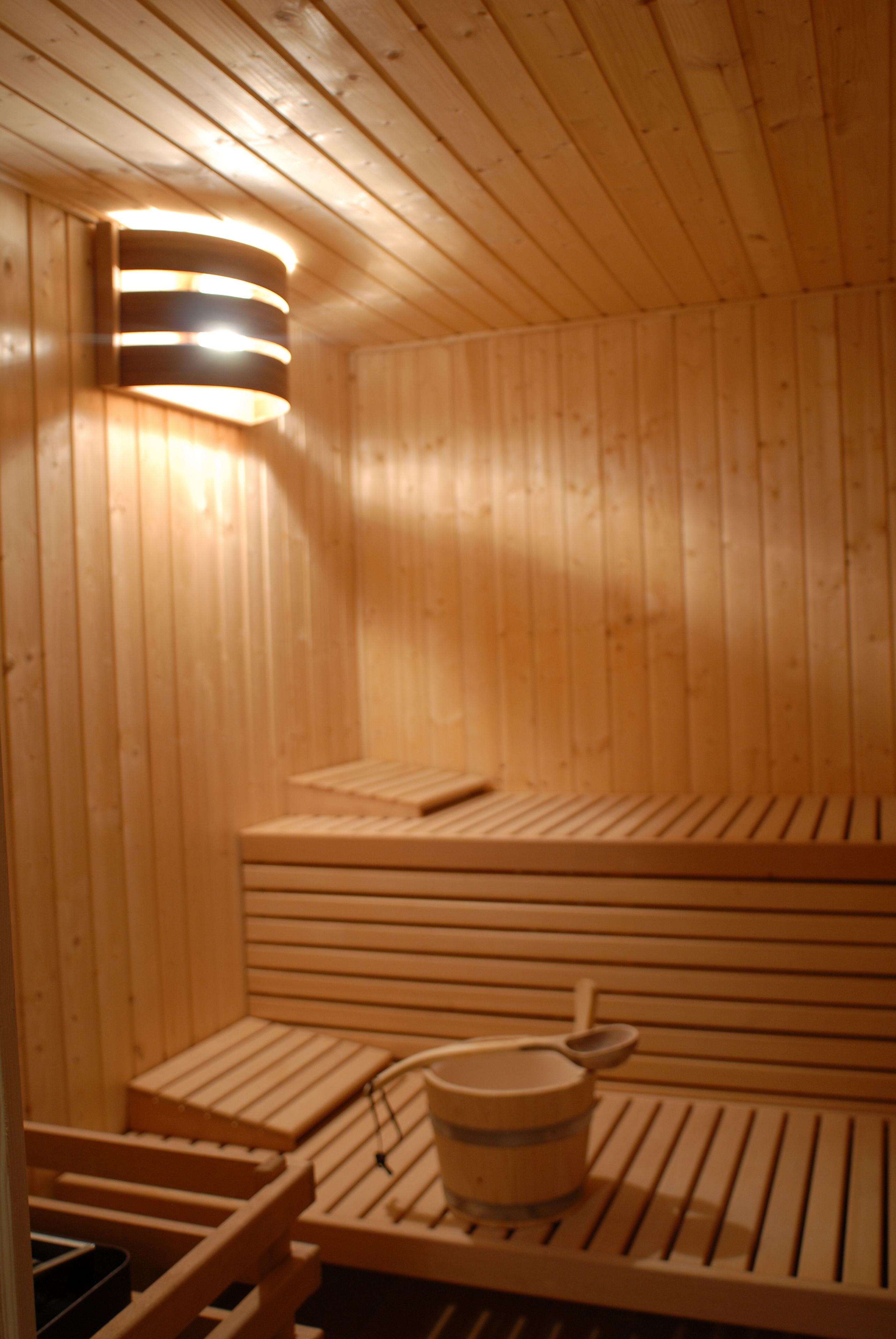 A wooden sauna with benches and a wooden bucket.