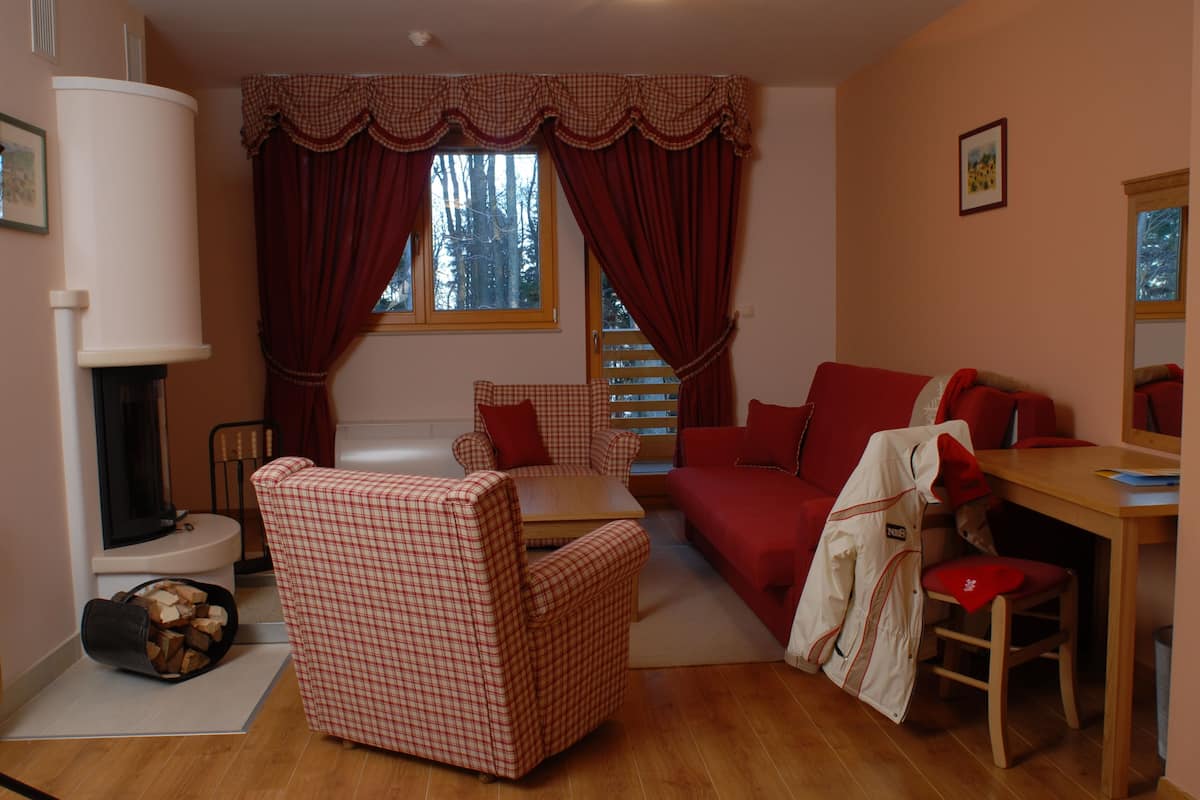 A cozy living room with a fireplace, checkered furniture, and a red sofa.