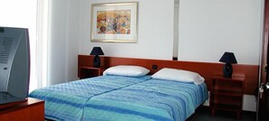 Une chambre d’hôtel avec un lit, deux tables de chevet, une télévision et un tableau au mur.