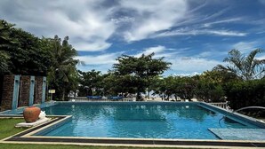 Una piscina con sillones de descanso y un césped decorativo.