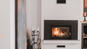 A modern fireplace with a white mantel and a black surround, accompanied by a black candle holder with three candles. - MB City Hotel (Izmir)
