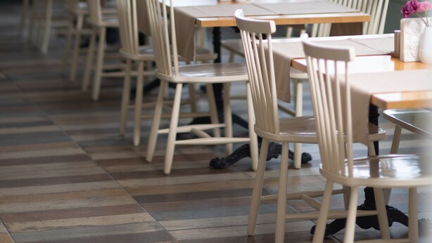 A restaurant with wooden tables and chairs, large windows, and indoor plants. - MB City Hotel (Izmir)