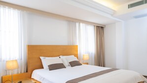 A hotel room with a large bed, wooden headboard, two bedside tables with lamps, and a wooden floor. - MB City Hotel (Izmir)
