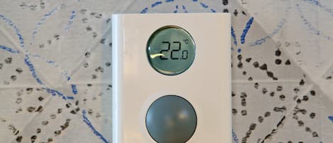 A thermostat with a digital display showing 22.0°C, a temperature adjustment knob, and a power button.