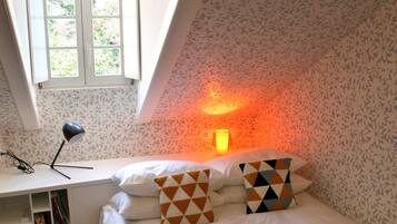 Un dormitorio con cama, escritorio, lámpara y ventana.
