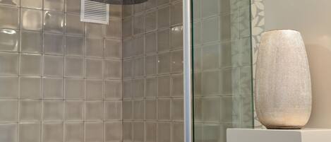 Ducha con cabezal de ducha de mano y zona de ducha con cerramiento de vidrio.
