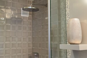 Ducha con cabezal de ducha de mano y zona de ducha con cerramiento de vidrio.
