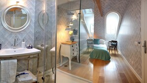 Un baño moderno con cabina de ducha de vidrio, un espejo redondo y un lavabo.