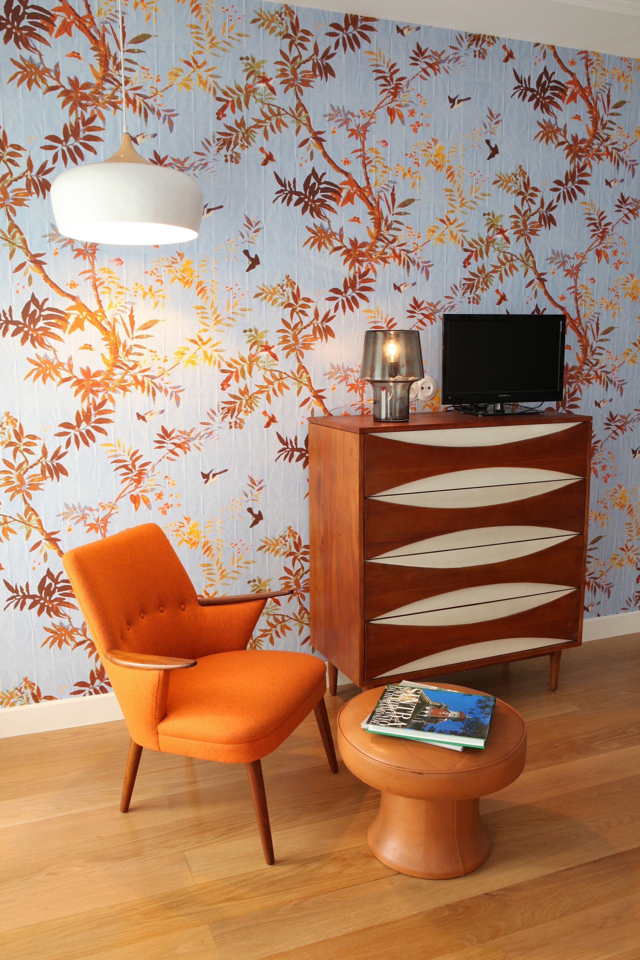 Une pièce comprenant un meuble en bois, un téléviseur, une chaise et une table avec un magazine.