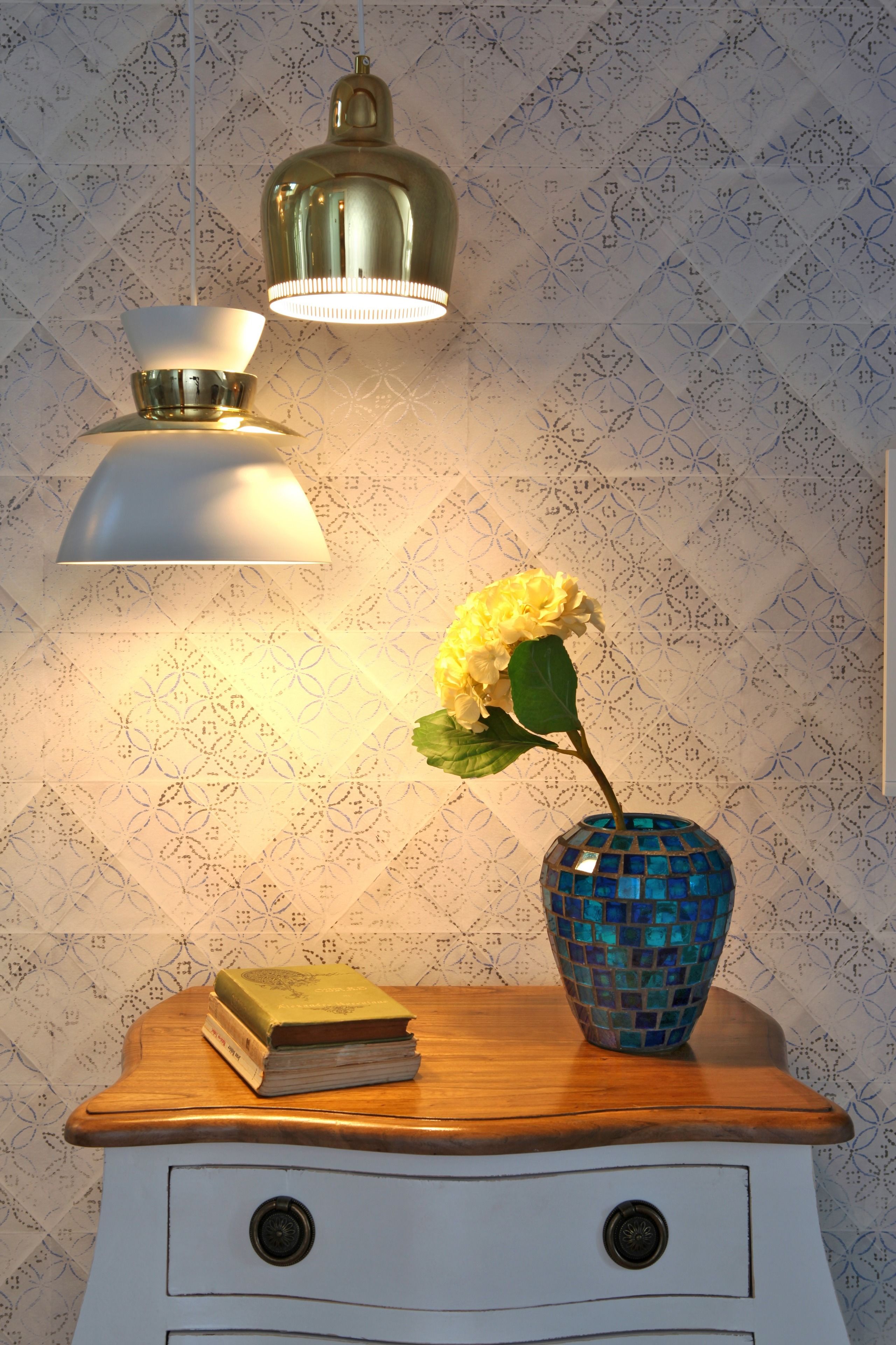 A wooden nightstand with a vase of flowers and a book.