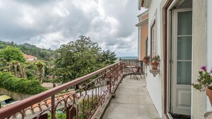 Un balcón con vista a un paisaje verde exuberante y una costa lejana.