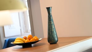 Una zona de comedor con una mesa de madera, un cuenco de fruta y un florero.