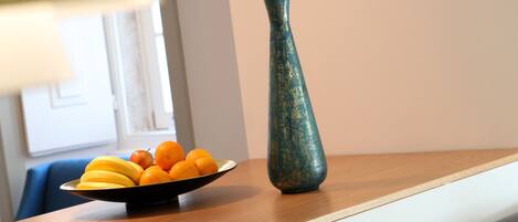 A dining area with a wooden table, a bowl of fruit, and a vase.
