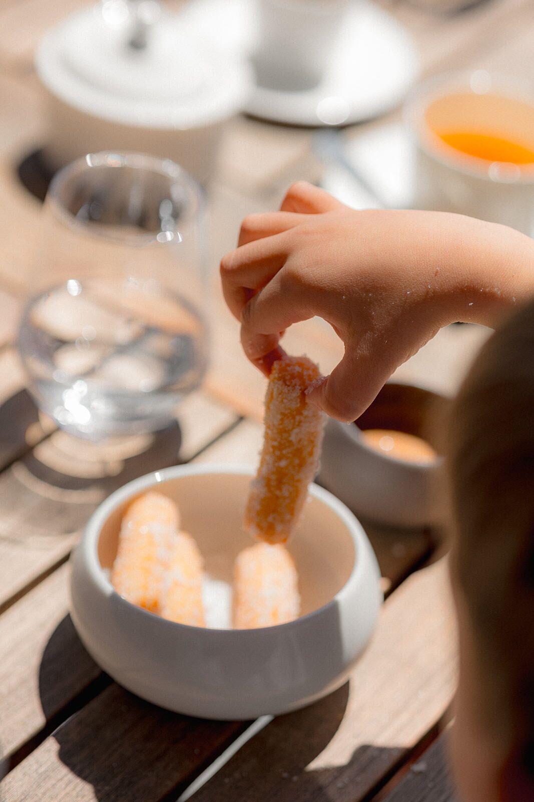 A hand dipping a chip into a bowl of sauce.