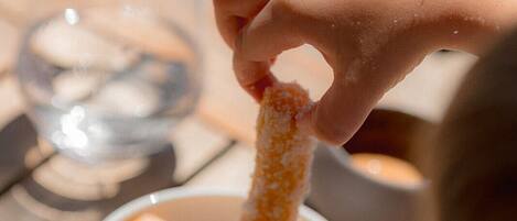 A hand dipping a chip into a bowl of sauce.