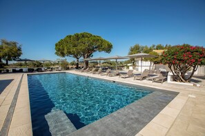 Una piscina al aire libre, sillones reclinables de piscina