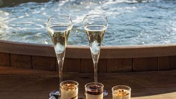 A tray of desserts and champagne glasses by a pool with a wooden deck and a view of a lake.