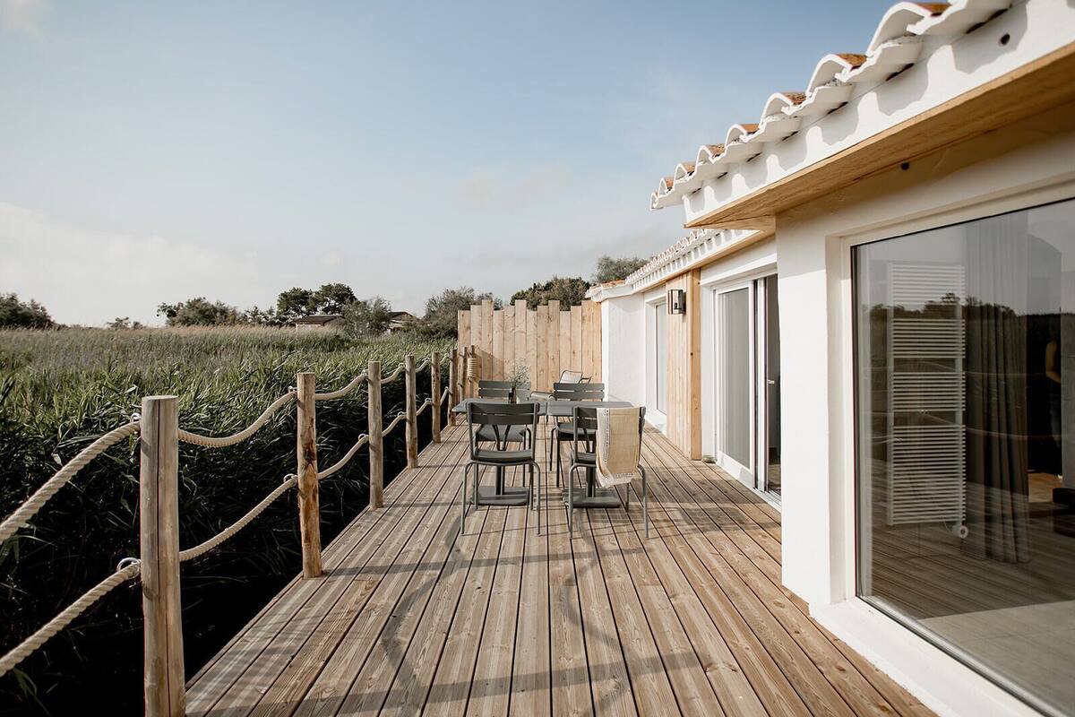 A wooden deck with outdoor seating and a glass door leading to a room.