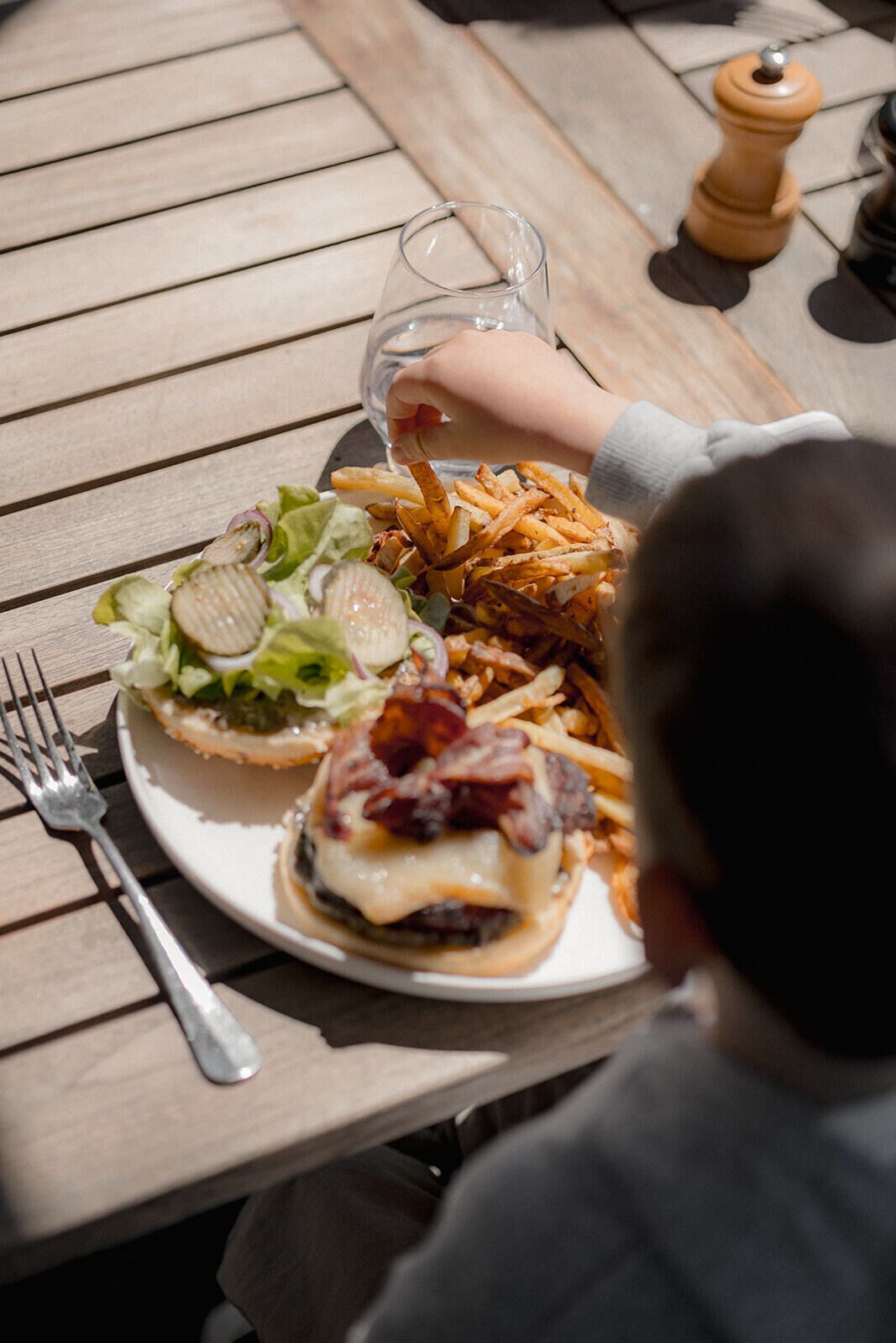 Une table à manger avec une assiette de nourriture, une fourchette et un verre d’eau.