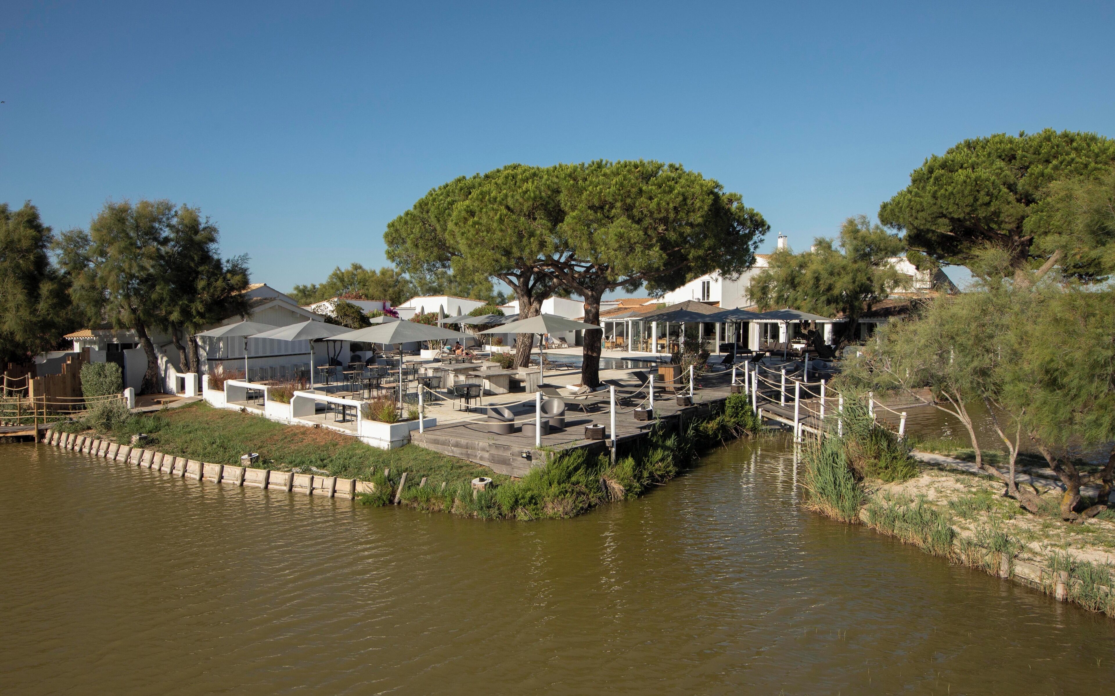 Propiedad a orillas del río con asientos al aire libre, una terraza de madera y piscina.